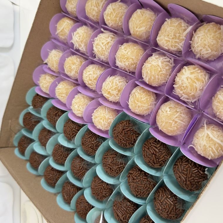 Bandeja com dezenas de brigadeiros em forminhas coloridas.